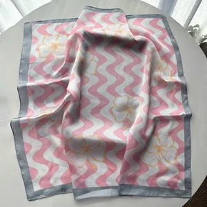 Macro detail of silk-like satin scarf featuring pink wave stripes and yellow floral prints