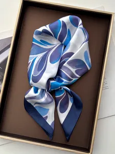 Detail of silk scarf with blue leaf pattern inside a luxury display gift box