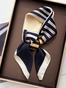 Détail d'un foulard en soie noué à rayures géométriques sur un plateau