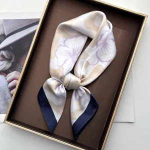 Close-up of silk scarf with purple floral print and blue hem on a vintage tray