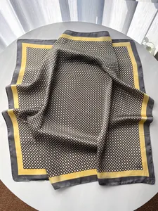 Détail d'un foulard carré en soie avec motif géométrique d'anneaux dorés et noirs élégants