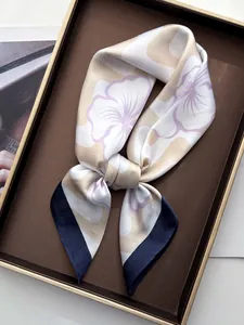 Close-up of floral silk scarf with cream base and blue edges in a luxury gift box