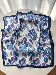 Detailed view of white silk scarf featuring blue and purple gradient leaf prints