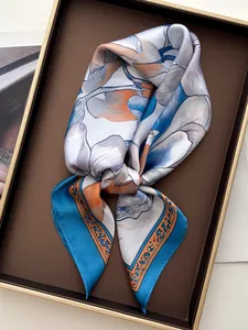 Dettaglio di un foulard in seta con motivo floreale e colori vivaci su un vassoio espositivo