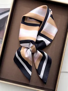 Detailed view of striped silk scarf with camel, pink and black patterns on display tray