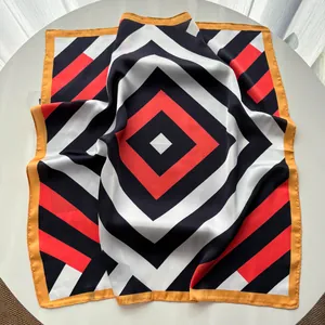 Detail of silk square scarf featuring red black geometric patterns and yellow stitched edges