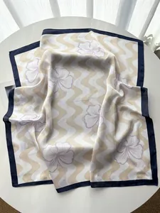 Macro view of silky floral scarf with wave pattern and navy blue borders on table