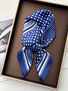 Detail of blue silk scarf with white polka dots and stripes on a luxury tray