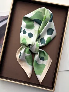 Nahaufnahme des eleganten Seidenschals mit grünem Leopardenmuster auf einem Ledertablett