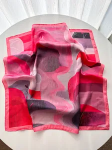 Close-up of pink abstract mountain print silk scarf draped on a white surface
