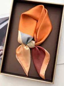 Detail of color-blocked geometric silk scarf displayed in a luxury dark brown gift box
