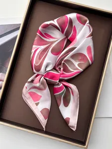 Detail of silk scarf with pink and brown leaf patterns displayed on a tray