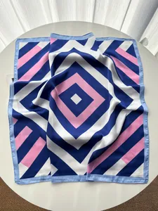 Close-up of geometric striped silk scarf with navy and pink rhombus patterns on a table