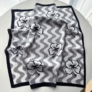 Detail of silk-like square scarf with elegant black and white wavy hibiscus floral print