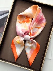 Detail of silk satin scarf featuring orange peony watercolor print on a brown tray