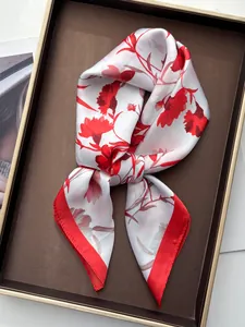 Detailed view of red carnation floral print on white silk square scarf in a tray