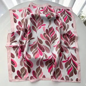 Detail view of satin silk square scarf with pink abstract leaf print and hemmed edges