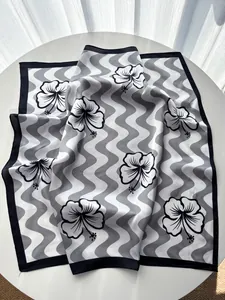 Macro view of wave patterns and black hibiscus flower print on a satin square scarf