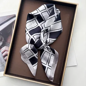 Detail eines Seidenschals mit schwarz-weißem Karomuster in einer Geschenkbox