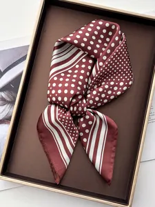 Detailed view of tied burgundy silk scarf with white polka dots on a dark tray
