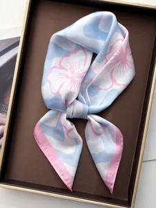 Close-up of silk square scarf with blue and pink floral print in a gold-framed tray