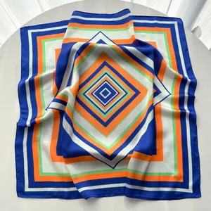 Close-up of geometric silk scarf featuring navy blue and orange square patterns