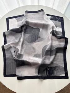 Detail of silk-feel scarf showing abstract mountain print and fine edge stitching