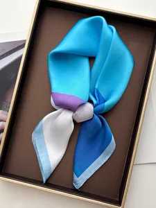 Detail view of a color-block silk scarf in blue and lilac on a decorative tray