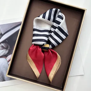 Gros plan du foulard en soie plié avec blocs rouges et rayures dans un coffret cadeau élégant