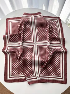 Detailed view of burgundy satin square scarf with white polka dots on a bright table