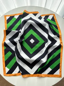 Macro detail of silk-like scarf featuring bold geometric patterns and orange rolled edges