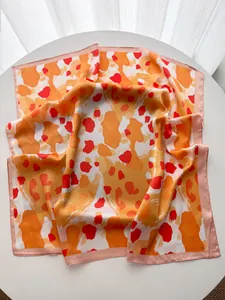 Detailaufnahme von elegantem Seidenschal mit lebhaftem orange-rotem Leopardenmuster-Print