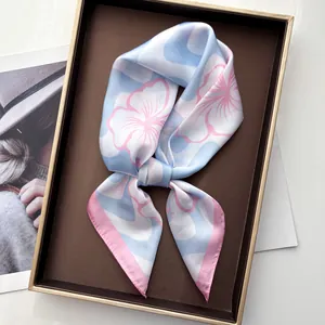 Detailed view of wavy floral silk scarf with pink rolled edges in a luxury gift box