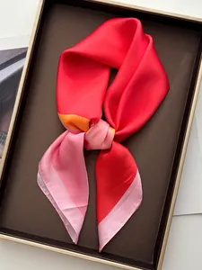 Detailed close-up of a vibrant silk-like scarf with red and pink color blocking in a tray