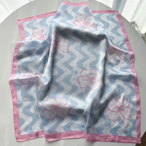 Close-up of wavy silk scarf with pink hibiscus floral pattern on blue background