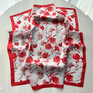 Detailed view of square silk scarf with vibrant red carnation floral print and satin border