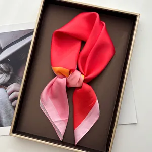Detailed view of tricolor satin scarf in red pink and orange folded in a luxury gift box