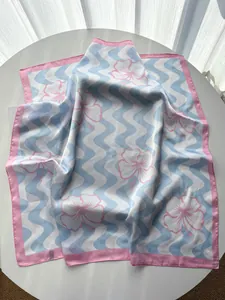 Macro shot of silk scarf detailing pink hibiscus flowers on blue wave pattern background