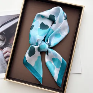 Detailaufnahme eines eleganten Seidentuchs mit blauem Abstraktmuster auf Tablett