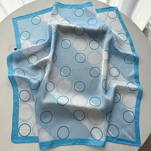 Detail of satin square scarf featuring geometric blue patterns and delicate stitched edges