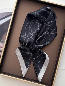 Detailed view of floral magnolia pattern on smooth silk scarf within a golden display tray