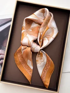 Dettaglio di un foulard in seta con motivi floreali arancioni e bianchi su un vassoio