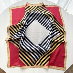 Détail d'un grand foulard en soie à rayures géométriques avec des bords roulés dorés