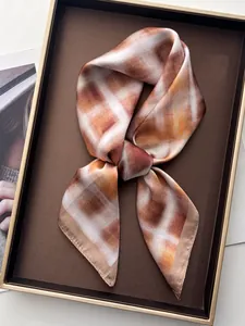 Detail van satijnen zijden sjaal met tie-dye ruitpatroon in aardetinten in doos