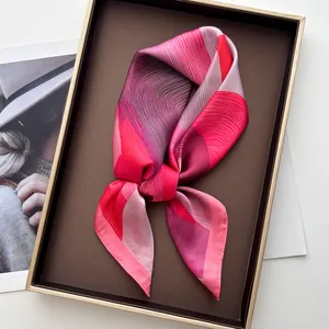 Elegant pink and purple gradient silk scarf with abstract wave print on a gold tray