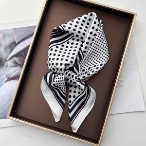 Detailed view of polka dot pattern silk-like scarf folded on a luxury display tray