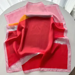 Detail of red and pink silk square scarf with floral print on white round table