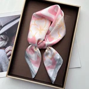 Fashionable floral silk scarf with pink and yellow wavy flower patterns in a tray