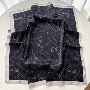Close-up of silk-satin square scarf with elegant white magnolia line art on black base