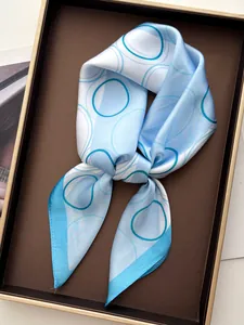 Close-up of sky blue silk scarf with geometric rings in a luxury gift box display